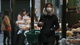 Seorang perempuan mengenakan masker saat berbelanja di Borough Market di London selatan selama penguncian nasional (lockdown) ketiga Inggris, Selasa (12/1/2021). Borough Market menjadi tempat pertama yang mewajibkan pemakaian masker di luar ruangan. (AP Photo/Alastair Grant)