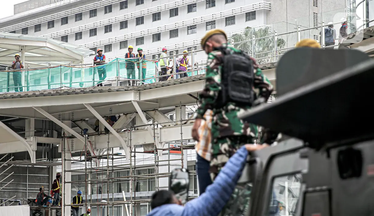 Pekerja melihat alat utama sistem senjata (alutsista) milik TNI saat perayaan HUT ke-77 TNI di Bundaran HI, Jakarta, Rabu (5/10/2022). Kegiatan yang diikuti oleh seluruh kesatuan jajaran TNI ini dalam rangka menyambut HUT ke-77 TNI. (Liputan6.com/Faizal Fanani)