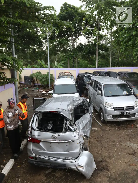 Petugas makukan evakuasi mobil yang rusak akibat terjangan Tsunami Selat Sunda di Terminal Carita, Banten, Selasa (25/12). Di terminal ini pemilik mobil dapat mengambilnya yang disertai dengan STNK. (Liputan6.com/Angga Yuniar)