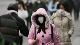 Seorang warga mengenakan masker ketika beraktivitas di distrik pusat bisnis Beijing, Tiongkok (21/12). Diberitahukan sejumlah anak-anak di beberapa kota di China seperti Beijing, Shanghai dan Hong Kong terkena masalah pernapasan. (Reuters/Jason Lee)