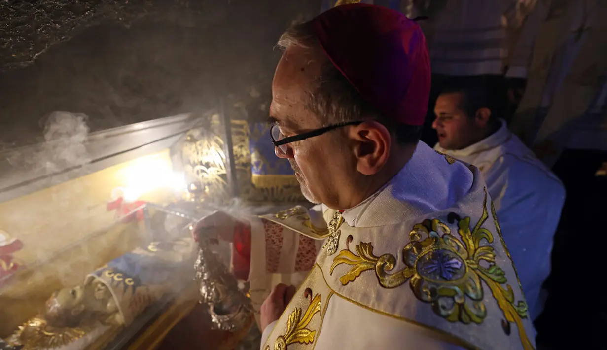 <p>Patriark Latin Yerusalem, Pierbattista Pizzaballa memimpin Misa Malam Natal di Kompleks Gereja Kelahiran Yesus, Bethlehem, Tepi Barat, Minggu (25/12/2022). Setelah dua tahun tutup karena COVID-19, jemaat kembali menghadiri ibadah tersebut kendati jumlahnya tidak sebanyak sebelum pandemi. (Ahmad Gharabli/Pool Photo via AP)</p>