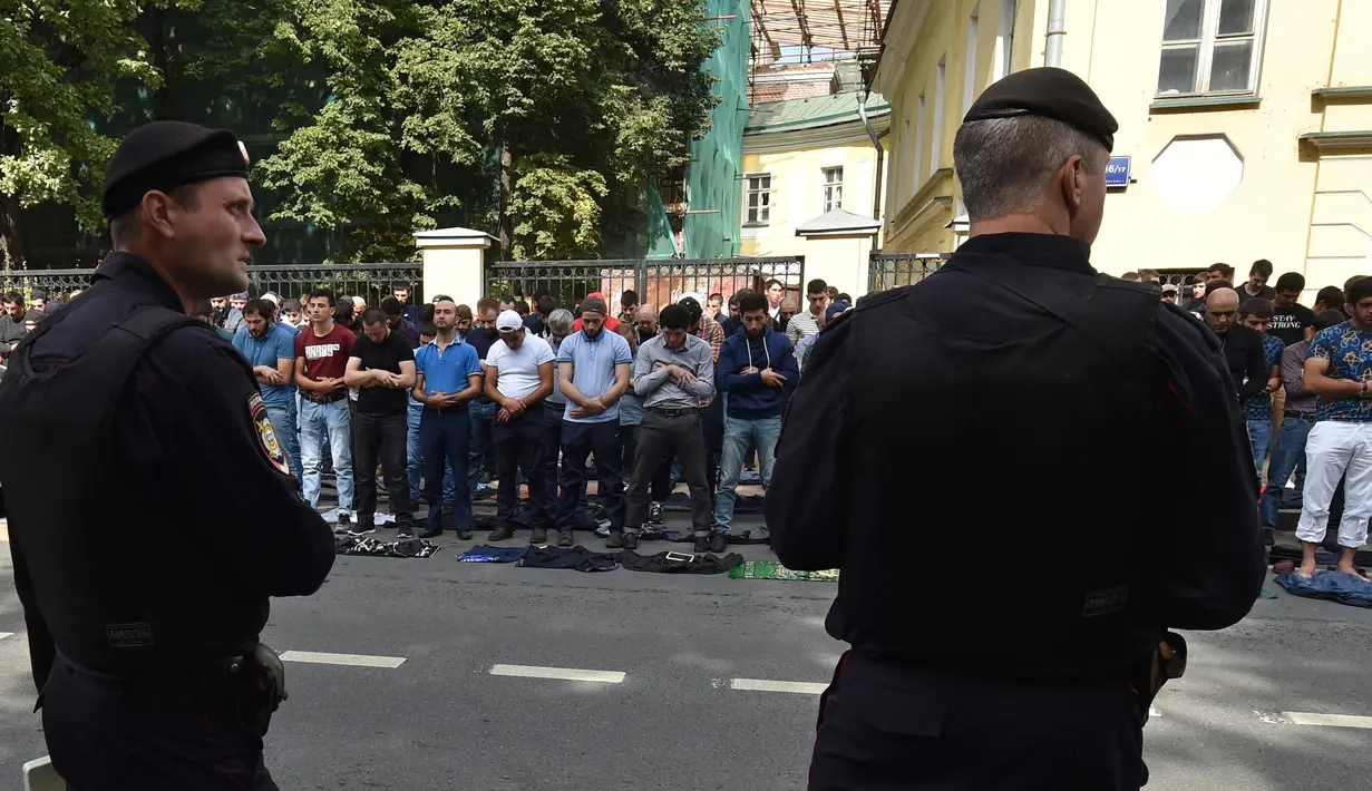 Petugas kepolisian berjaga saat warga muslim melaksanakan salat saat menggelar unjuk rasa di depan Kedubes Myanmar di pusat kota Moskow, Rusia, Minggu (3/9). Ratusan orang ikut dalam aksi solidaritas bagi Muslim Rohingya tersebut. (Vasily MAXIMOV/AFP)