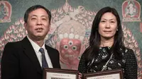 Liu Yiqian dan istrinya Wang Wei memegang foto berbingkai yang mereproduksi karya seni sulaman Tibet berusia 600 tahun yang disebut thangka di rumah lelang Christie's di Hong Kong pada 12 Maret 2015. Permadani sutra kuno Tibet telah memecahkan rekor lelang dunia untuk Tiongkok seni di Hong Kong setelah dibeli oleh Liu. (PHILIPPE LOPEZ/AFP)