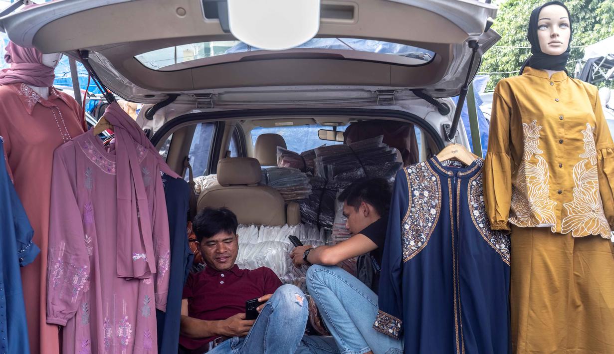 Langkah ini bertujuan untuk melindungi produsen lokal dan membantu industri tekstil bangkit dari krisis yang mengancam banyak pekerja dan menekan kinerja secara keseluruhan. Tampak dalam foto, pedagang menggunakan ponsel mereka sambil menunggu pelanggan di sebuah kios pakaian di salah satu pasar tradisional, Jakarta, Kamis 20 November 2025. (BAY ISMOYO/AFP)