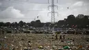 Penonton festival membawa barang-barang mereka saat berjalan melintasi lapangan yang dipenuhi sampah di akhir festival Glastonbury di desa Pilton di Somerset, barat daya Inggris, pada 26 Juni 2023. (AFP/Oli Scarff)