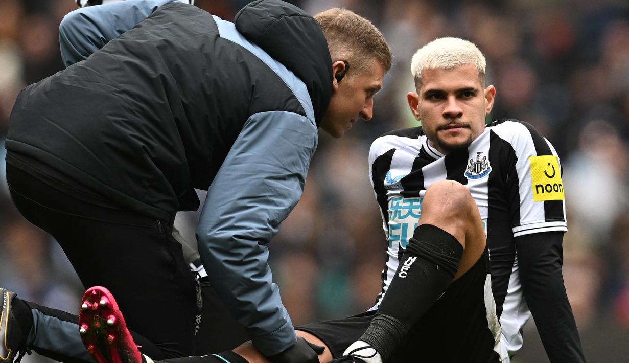 Gelandang Newwcastle Unied, Bruno Guimaraes mendapatkan perawatan dari tim medis setelah mengalami cedera saat menghadapi Manchester City pada laga lanjutan Liga Inggris 2022/2023 di Etihad Stadium, Manchester, Sabtu (4/3/2023) malam WIB. (AFP/Paul Ellis)