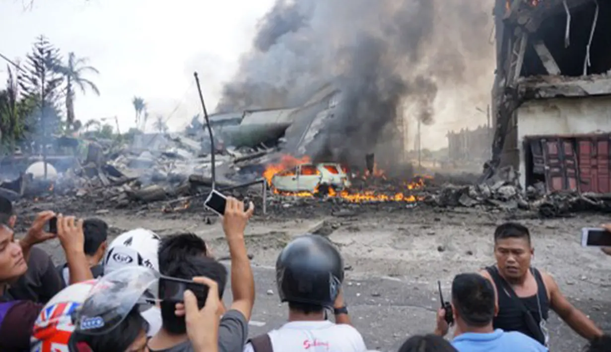 Sejumlah warga berkumpul di lokasi jatuhnya pesawat Hercules C-130 yang jatuh di kawasan perumahan, Medan, Selasa (30/6/2015). Hercules C-130 milik TNI AU jatuh tidak lama setelah lepas landas. (AFP PHOTO/Muhammad Zulfan Dalimunthe)