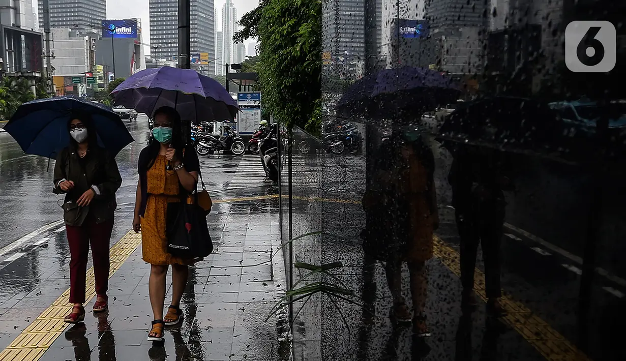 Pejalan kaki menggunakan payung saat hujan di kawasan Jakarta, Selasa (16/2/2021). Setelah memulai vaksinasi COVID-19 tahap pertama dengan sasaran petugas kesehatan, kini pemerintah menargetkan lansia dan petugas pelayanan publik untuk penerima vaksinasi tahap kedua. (Liputan6.com/Johan Tallo)