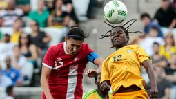 Marjory Nyaumwe berebut bola udara dengan pemain Kanada, Christine Sinclair di Grup F Olimpiade Rio 2016 di Korintus Arena, Brasil, (6/8). Atlet 29 tahun ini mengepang rambut gimbalnya ke atas yang jadi sorotan. (AFP PHOTO/Miguel SCHINCARIOL)