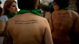 Wanita dengan tulisan protes di punggungnya ikut dalam unjuk rasa telanjang dada di Buenos Aires, Argentina, Selasa (7/1). Mereka melakukan protes atas kekerasan yang dilakukan aparat kepolisian terhadap perempuan tanpa bra. (AP Photo/Natacha Pisarenko)