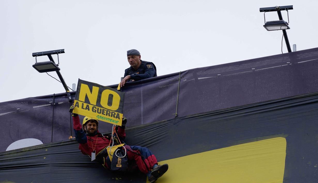 Sebelumnya, sebagaimana diketahui, serangan gabungan Amerika Serikat dan Israel terhadap Iran yang dimulai pada 28 Februari 2026 telah memicu perang terbuka di Timur Tengah. Tampak dalam foto, seorang petugas polisi mengamati aktivis Greenpeace yang membentangkan plakat bertuliskan "Tidak untuk Perang" saat ia menuruni gedung dengan tali untuk memprotes serangan Amerika Serikat (AS) dan Israel terhadap Iran, di Lapangan Puerta del Sol, Madrid, Spanyol, pada Selasa 10 Maret 2026. (Paul Hanna/AFP)