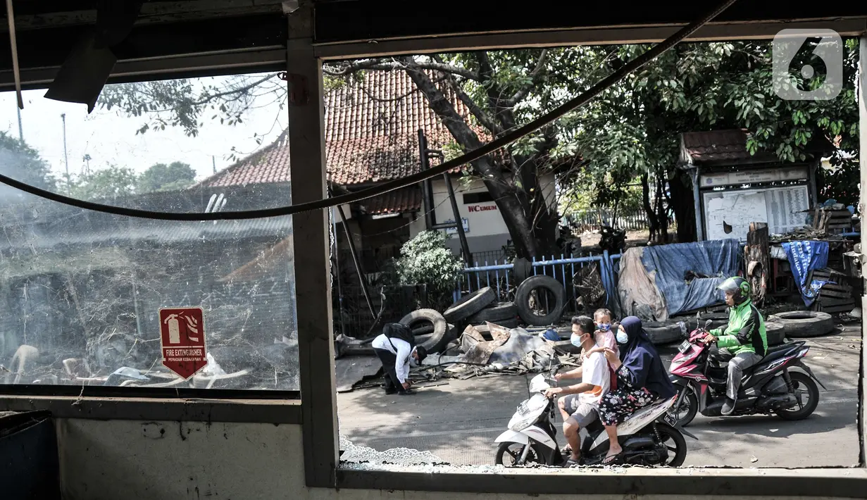 Warga melintas dekat 'kuburan' bus Transjakarta di Terminal Pulogadung, Jakarta, Kamis (8/7/2021). Bangkai bus Transjakarta tersebut dimanfaatkan warga setempat dengan cara dipotong-potong serta jeroan bus dijual yang hasilnya untuk kebutuhan sehari-hari. (merdeka.com/Iqbal S. Nugroho)