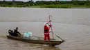 Pada Sabtu 20 Desember 2025, kelompok relawan Sahabat Sinterklas berbagi kebahagiaan Natal untuk untuk anak-anak di komunitas pedesaan dan tepi sungai di hutan hujan Amazon. Tampak dalam foto, relawan Jorge Alberto Barrozo, yang mengenakan kostum Sinterklas, berlayar dengan kano mengantarkan hadiah kepada anak-anak di komunitas tepi sungai di daerah pedesaan Careiro da Varzea, negara bagian Amazonas, Brasil pada Sabtu 20 Desember 2025. (Michael DANTAS/AFP)