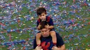 Penyerang Barcelona, Lionel Messi bersama anaknya saat parade kemenangan di stadion Camp Nou, Spanyol (7/6/2015). Barcelona untuk kelima kalinya meraih piala liga Champions usai mengalahkan Juventus 3-1 di Stadion Olympic. (REUTERS/Gustau Nacarino)