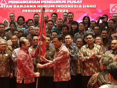 Menko Polhukam Wiranto memberikan bendera ke Ketua Umum Ikatan Sarjana Hukum Indonesia (ISHI) Amzulian Rifai saat pelantikan di Kemenkumham, Jakarta, Senin (30/7). Acara ini dalam rangka Pengukuhan PP ISHI 2018-2023. (Liputan6.com/Herman Zakharia)