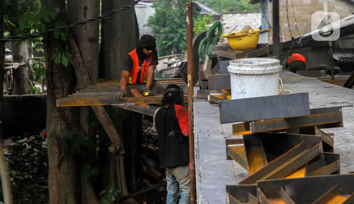 Pekerja menyelesaikan proyek pembangunan jembatan penghubung antarkampung di kawasan Pondok Pinang, Jakarta, Jumat (13/12/2019).  Jembatan yang menghubungkan permukiman di daerah Pondok Pinang dengan kawasan Bintaro tersebut ditargetkan rampung pada akhir Desember. (Liputan6.com/Faizal Fanani)