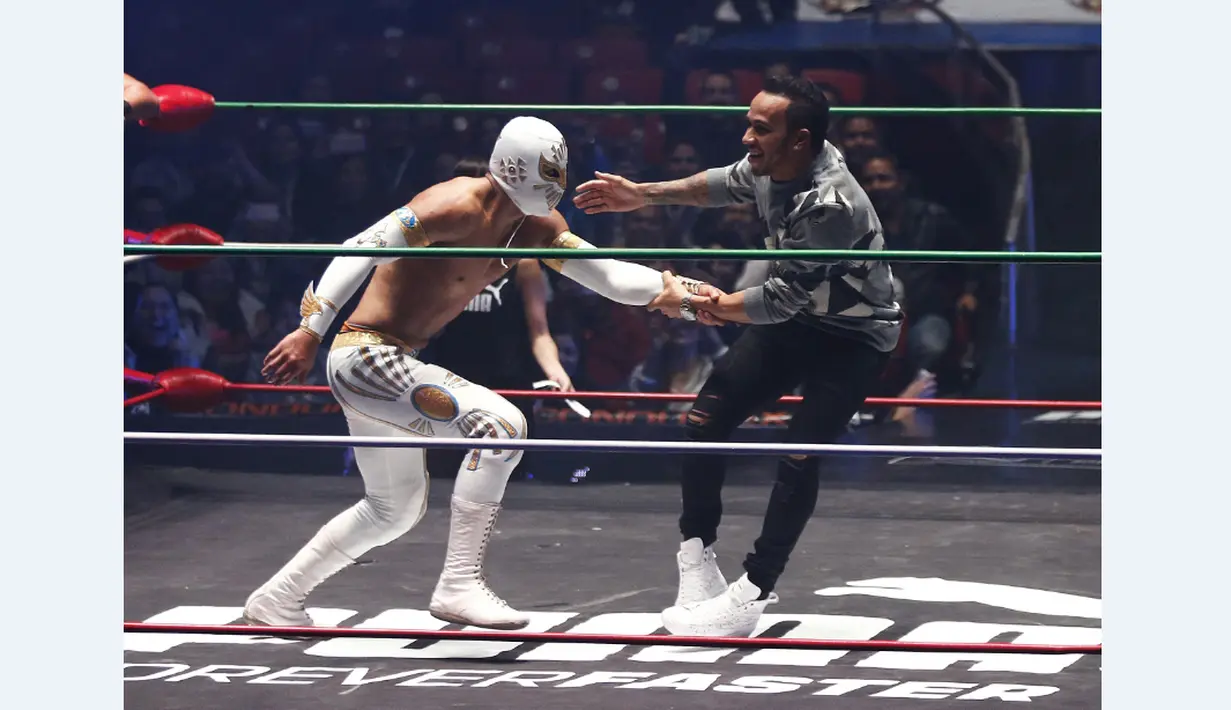 Pebalap F1 dari tim Mercedes GP, Lewis Hamilton bertanding gulat melawan bintang WWE dalam sebuah acara promosi di Coliseo Arena, Mexico City, (28/10/2015). (Reuters/Henry Romero)