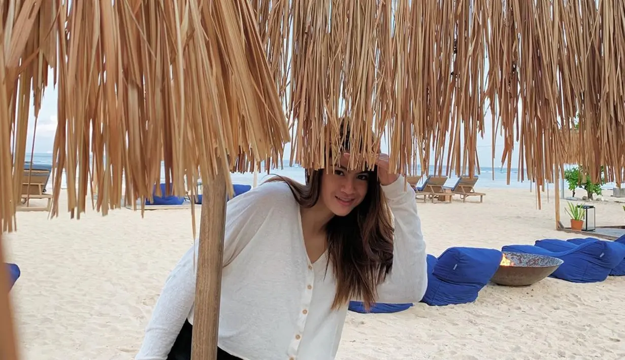 Banyak aktivitas yang bisa dilakukan oleh Hana Saraswati saat di pantai. Salah satunya adalah berpose foto bak sedang main petak umpet. Ya, fotonya saat sedang di pantai ini memang tampak lucu dengan pose Hana yang tersenyum tipis sambil seperti memantau sesuatu. (Liputan6.com/IG/@hananaho)