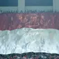 Suporter Indonesia membentangkan bendera raksasa saat laga Timnas Indonesia U-23 melawan Bahrain pada laga PSSI Anniversary Cu 2018 di Stadion Pakansari, Bogor, (26/4/2018). Bahrain unggul sementara 1-0. (Bola.com/Nick Hanoatubun)