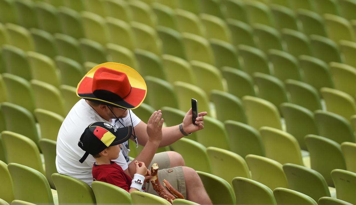 Seorang ayah bersama anaknya melakukan selfie saat menonton laga grup C Euro Cup 2016 antara Jerman melawan Irlandia Utara di Stadion Olympic, Jerman. (21/6/2016). (AFP/Christof Stache)