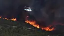 Sebuah helikopter membawa air untuk memadamkan kebakaran hutan di Benitatxell dekat Alicante, Spanyol, Senin (5/9). Sedikitnya 1.000 orang terpaksa diungsikan ke tempat yang lebih aman dari sejumlah vila. (REUTERS / Heino Kalis)