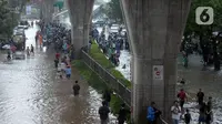 Warga menyusuri Jalan Kapten Tendean yang terendam banjir, Jakarta, Sabtu (20/2/2021). Banjir yang disebabkan curah hujan tinggi memutus akses lalu lintas di Jalan Kapten Tendean. (merdeka.com/Imam Buhori)