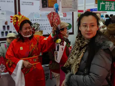 Seorang pekerja mengenakan kostum dewa keberuntungan untuk menarik pelanggan ke kiosnya saat bazar menyambut Tahun Baru Imlek di Beijing, China, Minggu 1 Februari 2026. Jelang perayaan Tahun Baru Imlek di China, suasana sibuk dan meriah mendominasi. (AP Photo/Andy Wong)