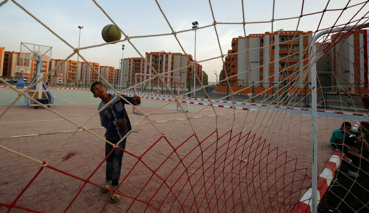Seorang anak bermain bola di sebuah lapangan yang berada di proyek rumah susun Tahya Misr di Al-Asmarat, Kairo, Mesir, 2 Juni 2016. Proyek rusun ini didirikan di tanah yang dahulunya merupakan permukiman kumuh. (REUTERS/Amr Abdallah Dalsh)