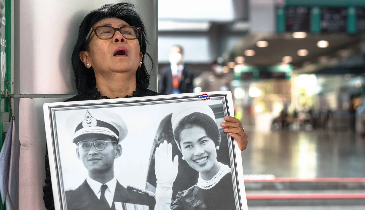 Seorang pelayat Thailand, Kanjana Malaithong, memegang potret Ratu Thailand yang telah wafat, Sirikit Kitiyakara, dan Raja Thailand Bhumibol Adulyadej, sambil menangis di Rumah Sakit Chulalongkorn di Bangkok pada 25 Oktober 2025. (Chanakarn Laosarakham/AFP)