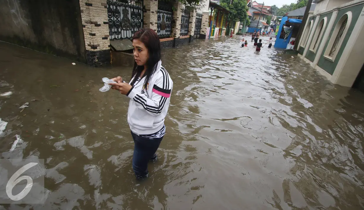 Warga melintasi banjir yang menggenangi Jalan Ketapang di kawasan Pasar Minggu, Jakarta, Selasa (4/10). Banjir yang berasal dari luapan Kali Anur tersebut menyebabkan Jalan Ketapang tidak bisa dilewati kendaraan. (Liputan6.com/Immanuel Antonius)