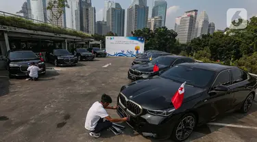 Petugas membersihkan mobil BMW i7 dan i5 di komplek GBK, Senayan, Jakarta, Jumat (3/5/2024). (Liputan6.com/Angga Yuniar)