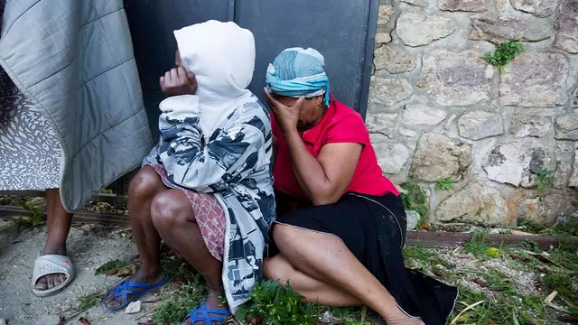 Staf pekerja Panti Asuhan Church of Bible Understanding menangis di luar rumah anak-anak, pagi hari setelah kebakaran mematikan terjadi di fasilitas di Kenscoff, di pinggiran Port-au-Prince, menewaskan 13 anak-anak.