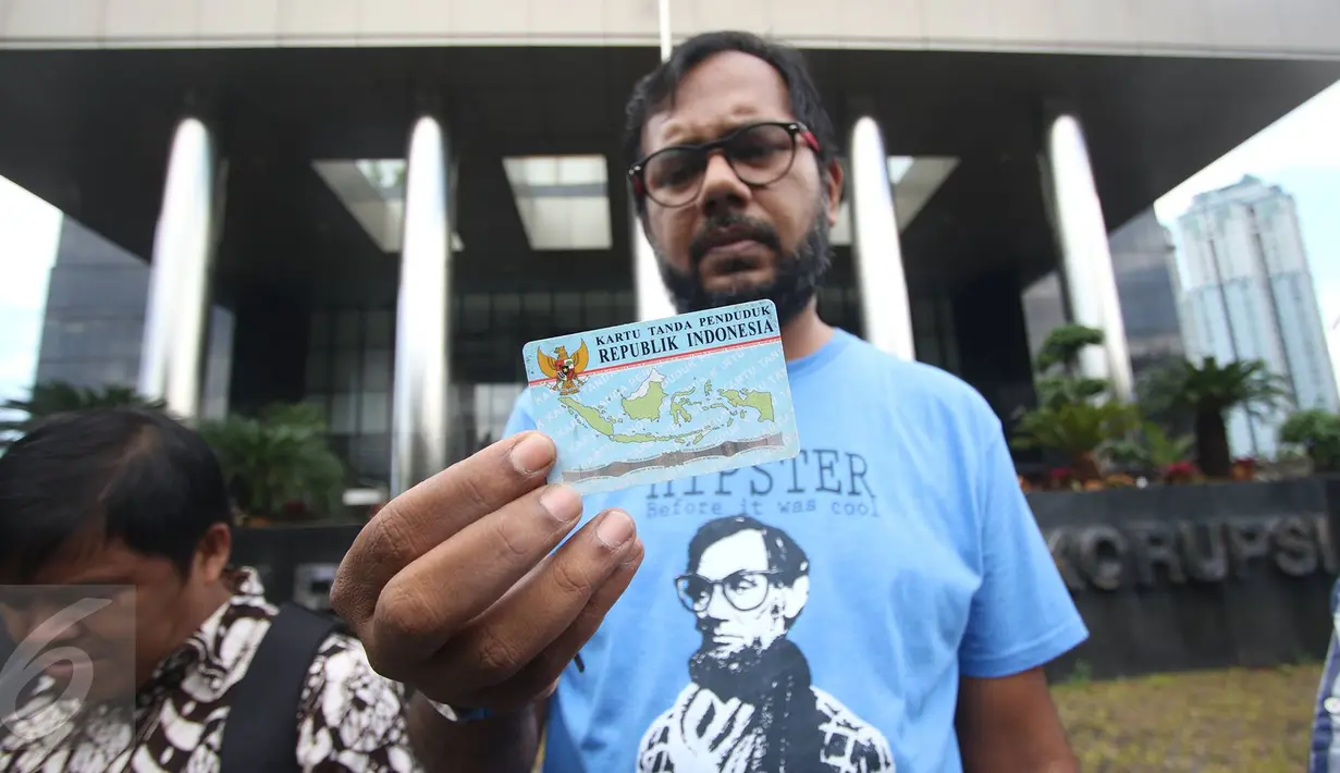Haris Azhar menunjukan KTP Elektronik saat melakukan aksi di depan Gedung KPK, Jakarta, Minggu (12/3). Aksi tersebut menuntut agar KPK mengusut kasus korupsi KTP Elektronik yang diduga melibatkan sejumlah pejabat negara. (Liputan6.com/Immanuel Antonius)