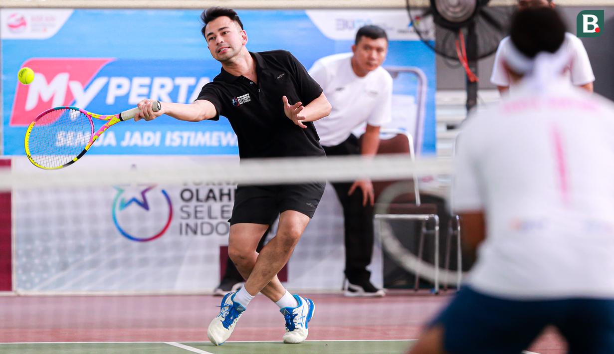 Selebritas Indonesia, Raffi Ahmad berusaha mengembalikan bola ke arah pasangan Rezky Aditya dan Tanta Ginting pada laga tenis nomor ganda putra Turnamen Olahraga Selebriti Indonesia di GOR UNJ, Jakarta, Minggu (30/07/2023). Raffi yang berpasangan dengan Deddy Mahendra Desta menang dengan skor 4-6, 6-4, dan 6-4. (Bola.com/Bagaskara Lazuardi)