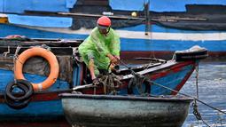 Badan Meteorologi Nasional Vietnam memperkirakan, Topan Kalmaegi akan disertai gelombang setinggi delapan meter atau 26 kaki dan badai yang kuat. Tampak dalam foto, seorang pria mengikat perahu untuk melindunginya dari dampak Topan Kalmaegi di Pelabuhan Perikanan Quy Nhon, Provinsi Gia Lai, Vietnam Tengah, pada 6 November 2025. (Nhac NGUYEN/AFP)