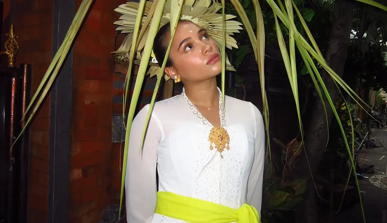 Aurora Ribero tampil anggun dengan balutan busana adat khas Bali. Ia mengenakan kebaya berwarna putih dengan selendang kuning cerah yang diikatkan di pinggang, memberikan aksen ceria pada penampilannya. (Liputan6.com/IG/@auroraribero)