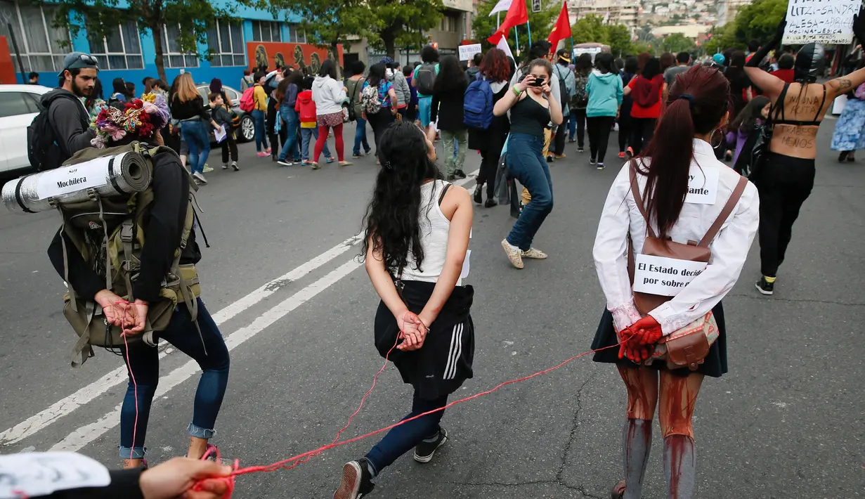 Para wanita berjalan dengan tangan terikat saat memperingati Hari Anti Kekerasan Perempuan di Santiago, Chile (25/11). (REUTERS/Rodrigo Garrido)