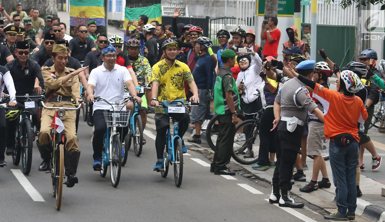 Presiden Joko Widodo atau Jokowi menyapa warga saat mengikuti Bandung Lautan Sepeda, Sabtu (10/11). Jokowi berpakaian khas Sutomo atau Bung Tomo dalam kegiatan tersebut. (Liputan6.com/Angga Yuniar)