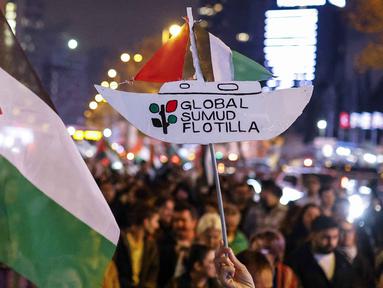 Seorang pengunjuk rasa memegang plakat penghormatan kepada Global Sumud Flotiila saat berunjuk rasa dalam solidaritas kepada warga Palestina dan mengutuk pencegatan armada oleh tentara Israel, di Istanbul, Turki pada 2 Oktober 2025. (KEMAL ASLAN/AFP)