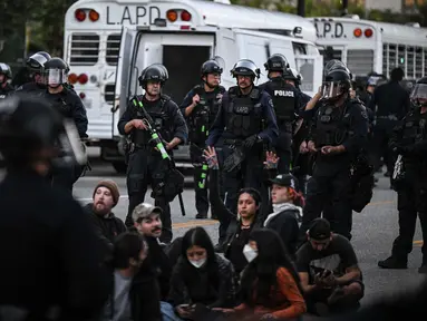 Petugas polisi berdiri di sekitar pengunjuk rasa yang ditangkap setelah demonstrasi menentang operasi imigrasi federal di dekat Balai Kota Los Angeles, Amerika Serikat pada 11 Juni 2025. (RONALDO SCHEMIDT/AFP)