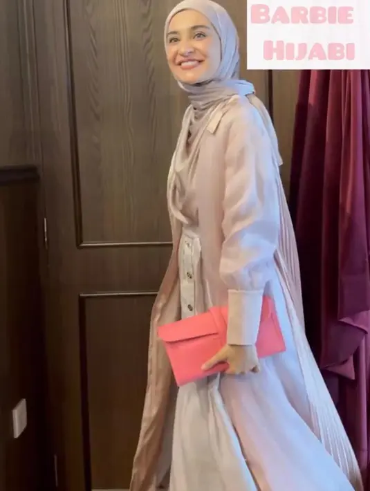 Shireen Sungkar bergaya ala Barbie Hijabi dengan long outer, maxi skirt, dan hijab serba baby pink dan clutch warna pink cerah. [@zaskiasungkar15]