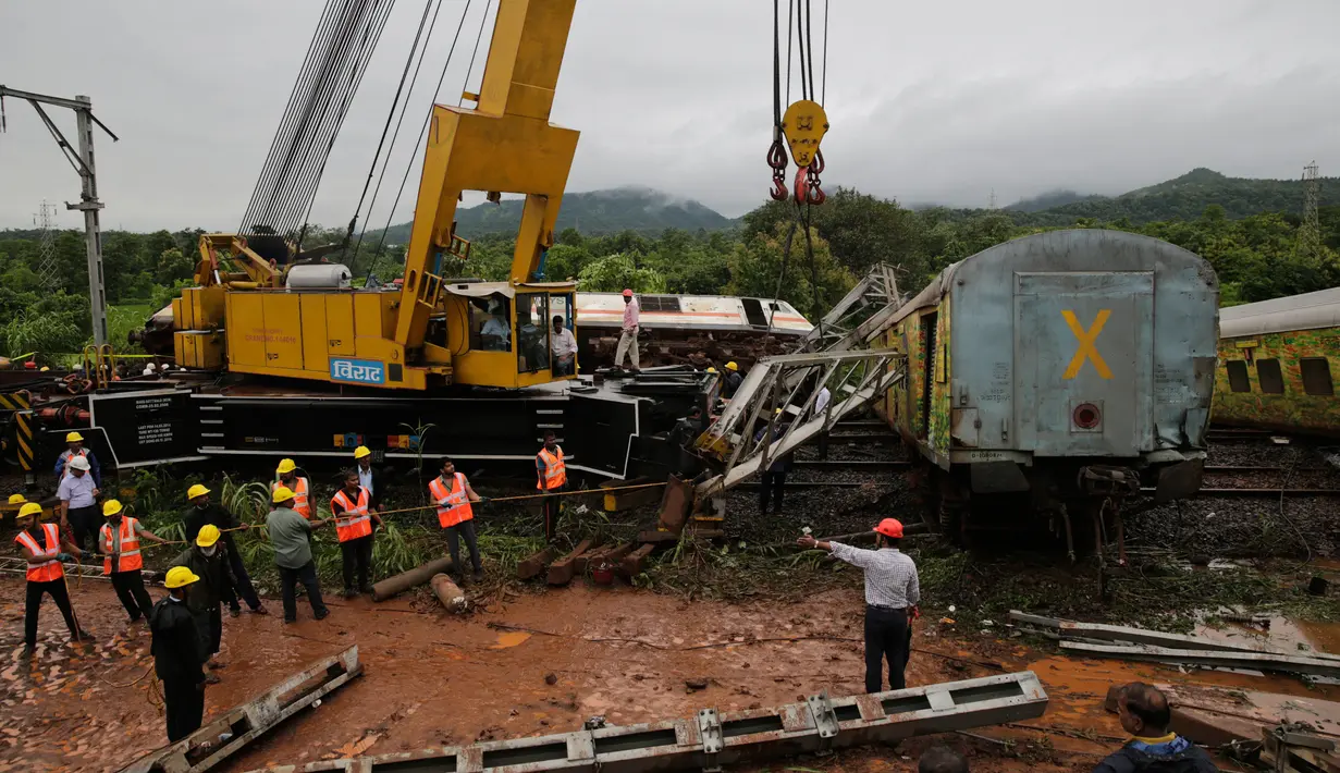 Petugas menggunakan alat berat mengevakuasi kereta yang tergelincir di Asangaon, India (29/8). Sejauh ini tidak ada korban jiwa akibat kecelakaan kereta tersebut. (AP Photo / Rafiq Maqbool)