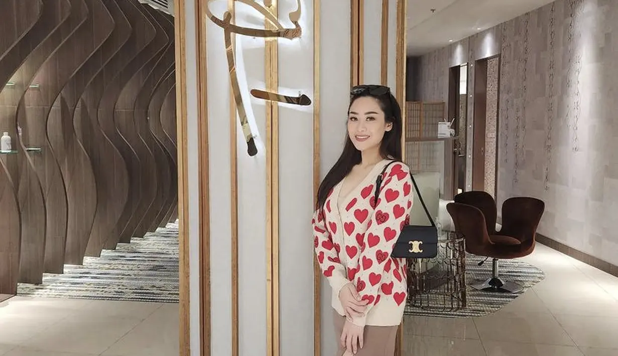 Poppy tampil dengan cardigan lambang love dipadukan slit skirt coklat, ia pun membawa shoulder bag hitam dari Celine. [Instagram/@poppycapella_]