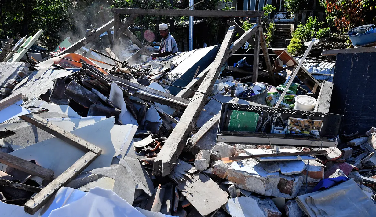 Seorang pria menyelamatkan barang berharga dari puing rumah yang rusak di Menggala, Lombok Utara, Rabu (8/8). Warga terdampak gempa Lombok mulai mengamankan barang berharga miliknya karena kuatir dijarah pihak tidak bertanggung jawab. (AFP/ADEK BERRY)