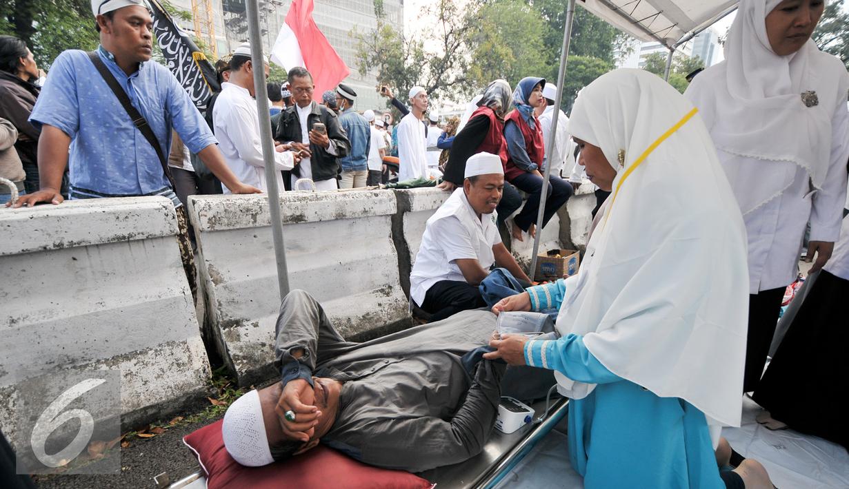 Seorang demonstran yang kelelahan diberikan pertolongan, Jakarta, Jumat (4/11). Massa yang datang ke posko ini rata-rata yang usianya sudah separuh baya, di atas 45 tahun. (Liputan6.com/Yoppy Renato)