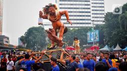 Umat Hindu mengarak ogoh-ogoh saat hari bebas berkendara di kawasan Bundaran HI, Jakarta, Minggu (12/3/2023). Ogoh-ogoh sendiri dalam kebudayaan Bali biasa menggambarkan kepribadian Bhuta Kala yang dalam ajaran Hindu Dharma merupakan kekuatan (Bhu) alam semesta dan waktu (Kala) yang tak terukur dan tak terbantahkan. (Liputan6.com/Angga Yuniar)