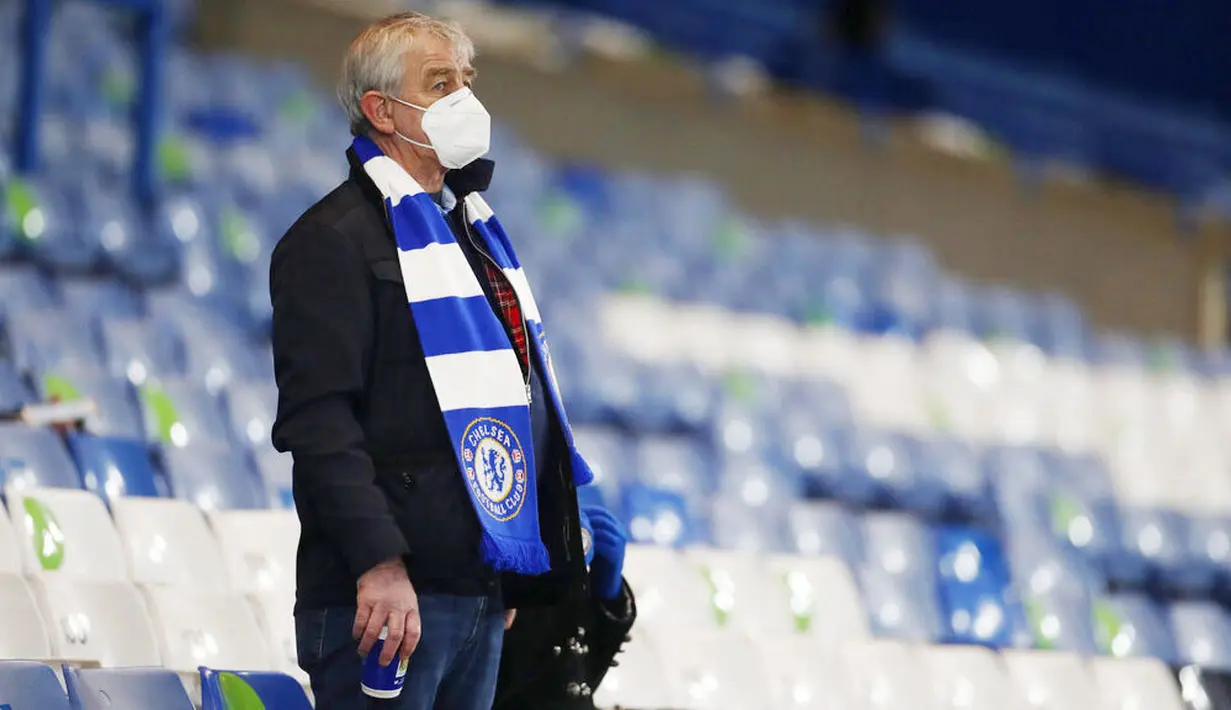 Suporter Chelsea mamakai masker saat menyaksikan pertandingan Chelsea melawan Leeds United pada laga Liga Inggris di Stadion Stamford Bridge, Sabtu (5/12/2020). (Matthew Childs/Pool via AP)