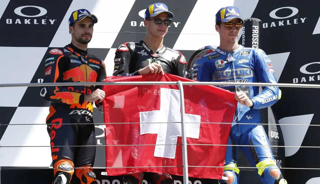 Bukan hanya dari Fabio Quartararo, tapi bagi Miguel Oliviera serta Joan Mir yang finish di urutan kedua dan ketiga kemenangan mereka didedikasikan bagi Jason Dupasquier dengan membentangkan bendera Swiss negara asal pebalap Moto3 tersebut. (Foto: AP Photo/Antonio Calanni)