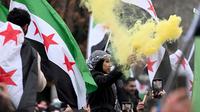Pemberontak yang dipimpin oleh kelompok Islamis menggulingkan penguasa lama Suriah, Bashar al-Assad. Tampak dalam foto, anggota komunitas Suriah melambaikan bendera Suriah dan menyalakan suar pada tanggal 8 Desember 2024 di Berlin, Jerman, untuk merayakan berakhirnya kekuasaan rezim Bashar al-Assad. (RALF HIRSCHBERGER/AFP)