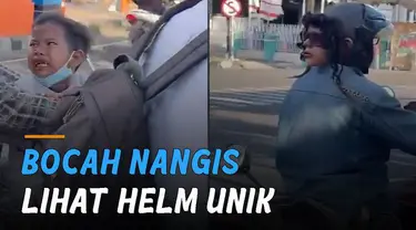 Bocah laki-laki yang berada di belakang pengendara motor menangis ketakutan melihat helm unik itu.